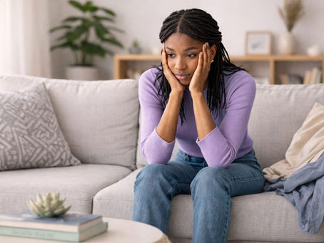 Mulher sentada no sofá com expressão pensativa em momento de ansiedade e reflexão