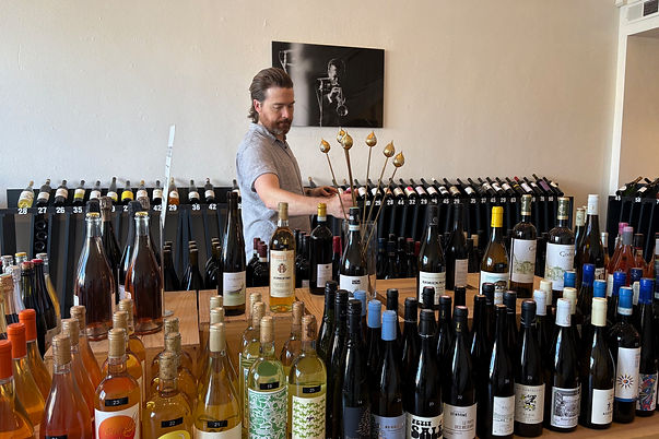 Damien Carney at Avinage in Petaluma, California arranges bottles of European wines on a d
