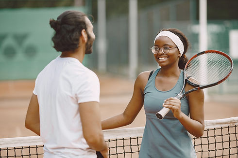 Asian Tennis players at the net laughing and talking about tennis