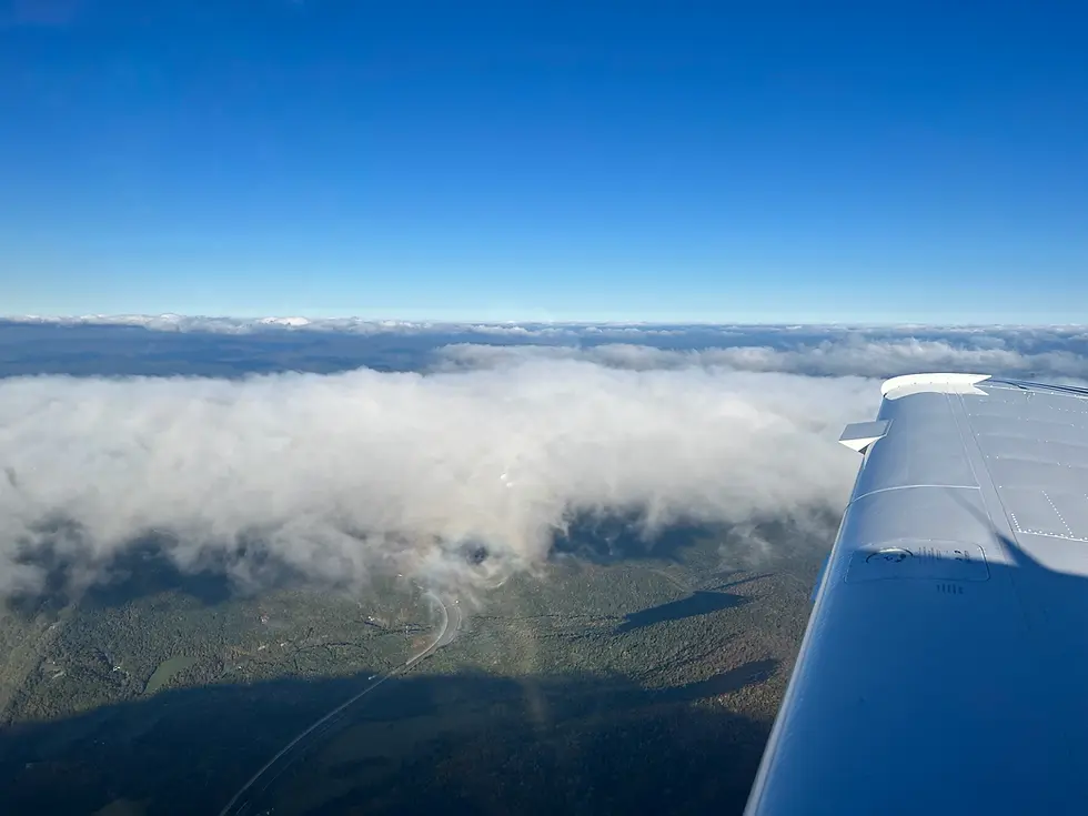 Aerial view from an aircraft wing looking out over clouds, representing the gift of flying