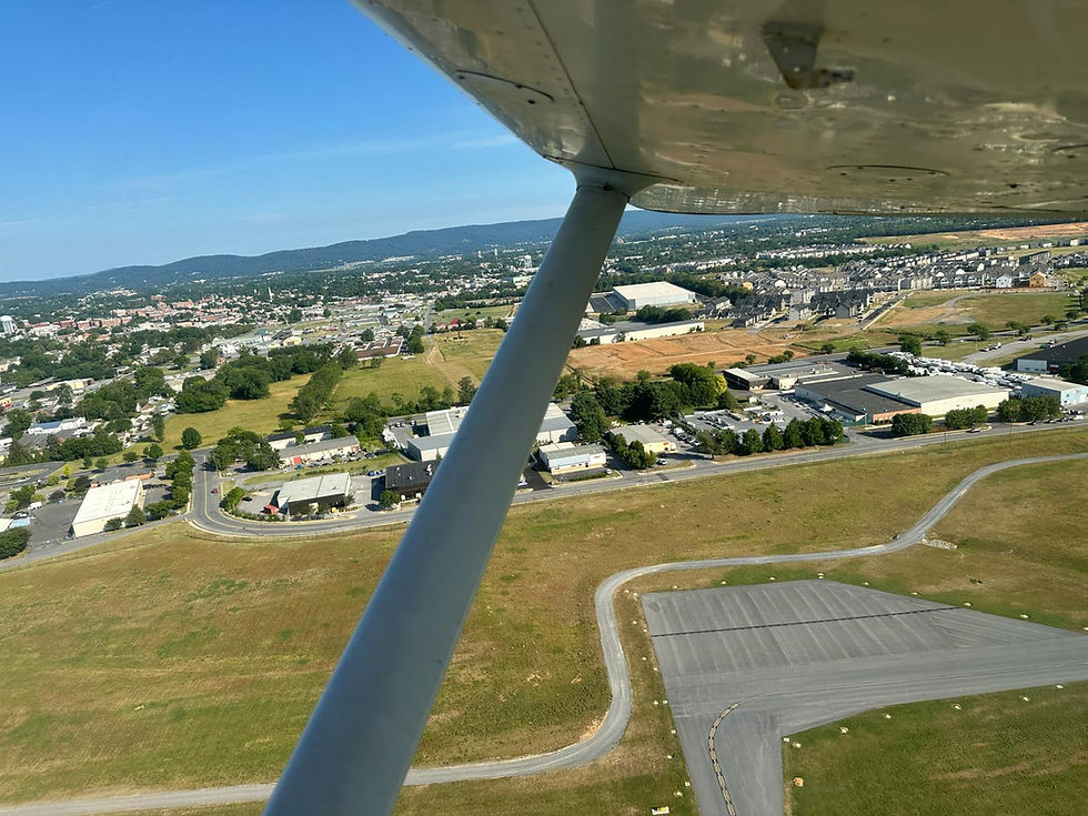 Aerial view from an aircraft wing overlooking a small town and airport runway, representing the Adventure tour package