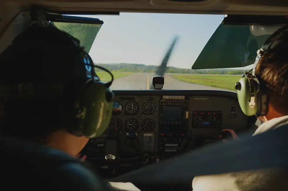 View from inside a Cessna 172 cockpit during a training flight, with an instructor and student in view