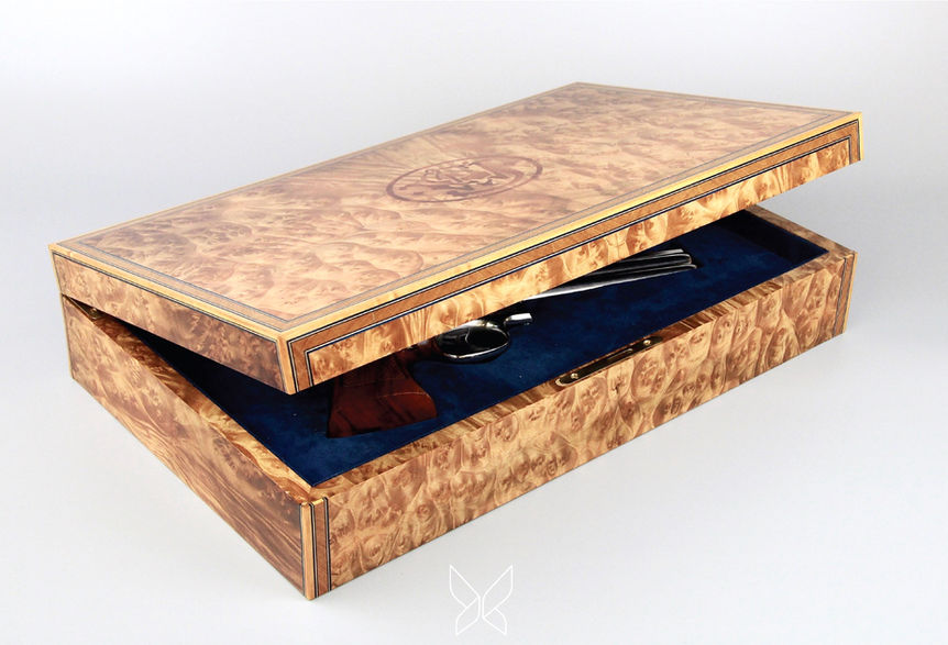 Open handcrafted wooden weapon box with blue velvet interior and engraved lid emblem.