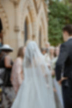 Eliza and Damon greeting smiling wedding guests outside the church