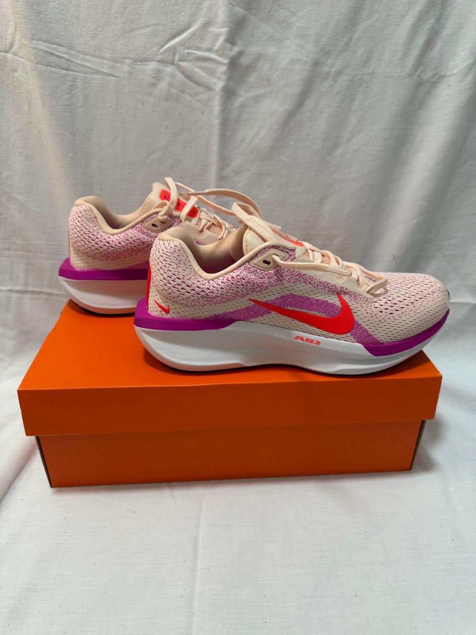 tenis nike air winflo 11 na cor rosa claro, com detalhes roxo e laranja