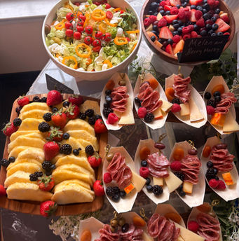 Full overhead grazing table with salad bowl, berry medley, pineapple board, and charcuterie cones for NJ catering