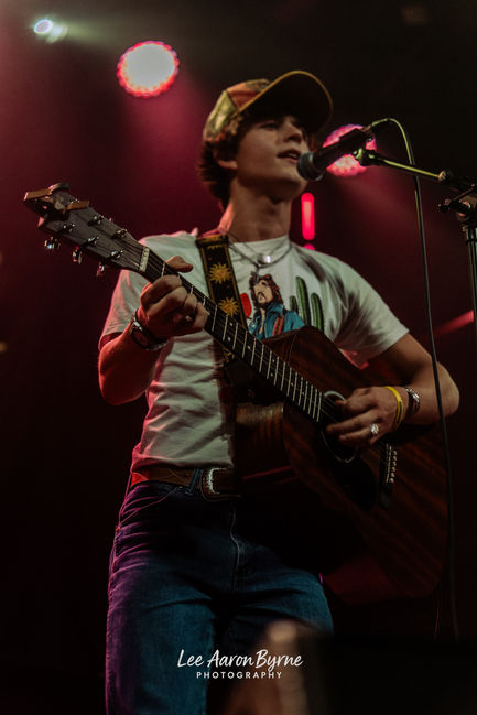 Musician performing on stage with guitar and microphone.