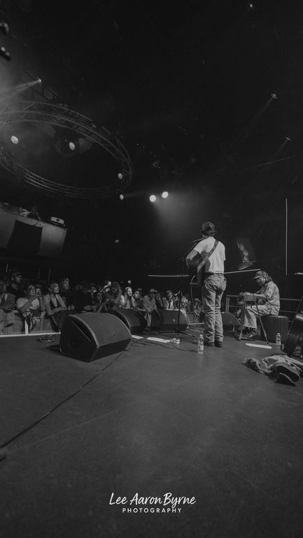 Musicians performing on stage with audience watching.