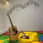 a guitar and a bean bag with a puppet and musical notes on the wall