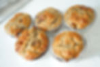 five golden high protein banana oat muffins in wrappers on a white counter.