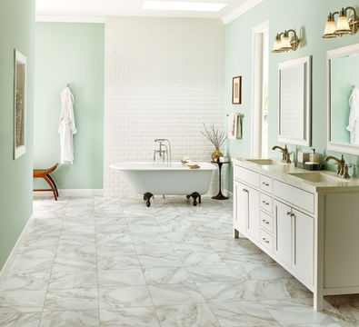 A bathroom painted in pastel green with a bathtub and two sinks