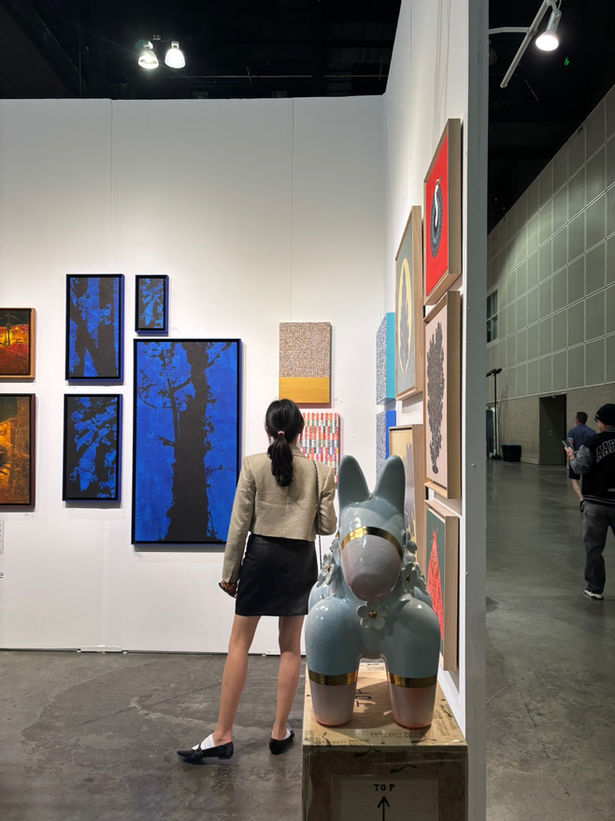 back of a woman looking at an artpiece at an art fair