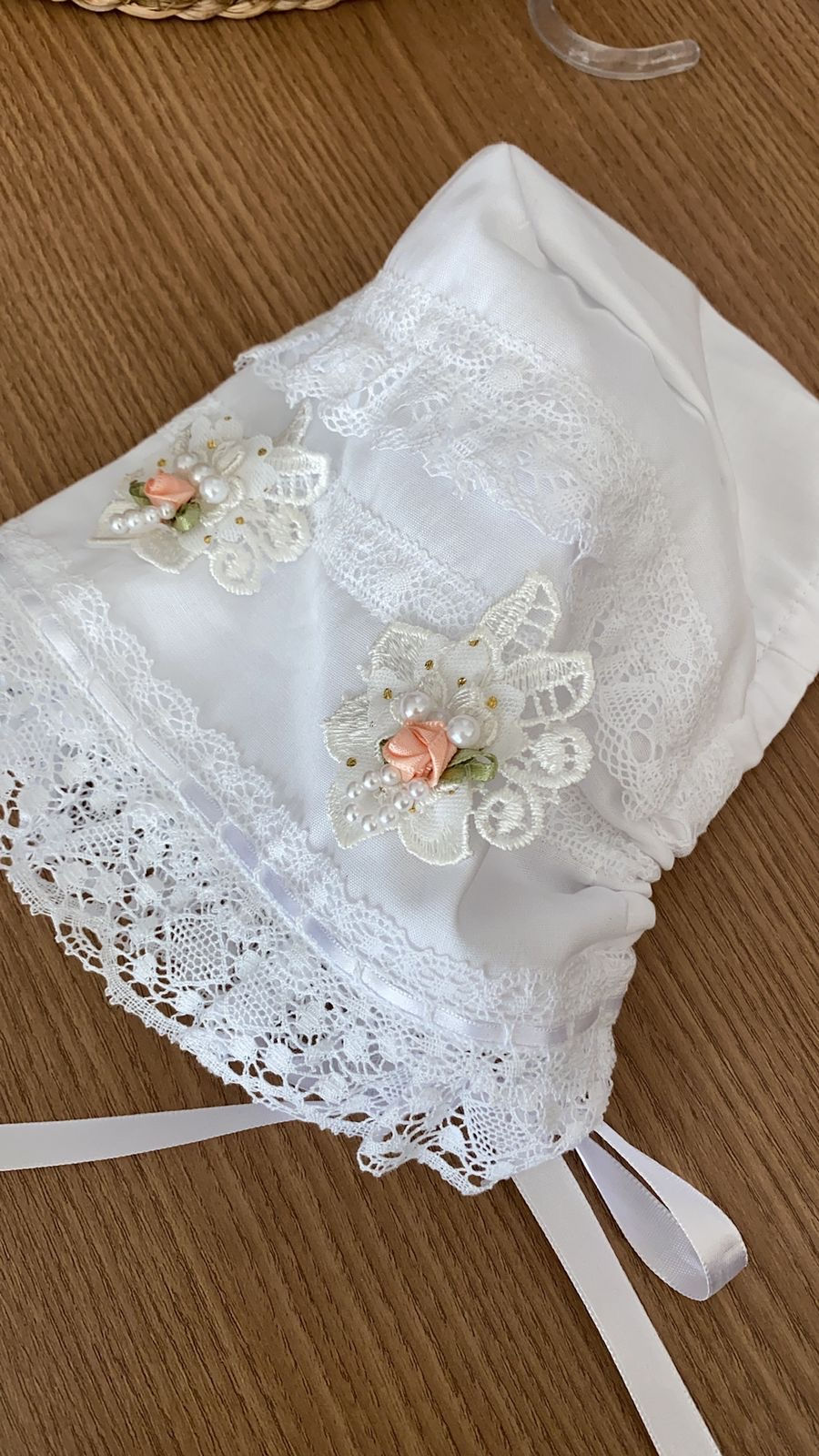 Miniatura: Feita com cambraia, um tecido leve e transparente, esta touca oferece uma sensação suave e suave ao toque, proporcionando conforto ao bebê.