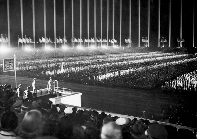 Hitler addressing a crowd of several hundred thousand at the 1937 Nuremberg Rally. Over 150 anti-aircraft search lights were used to create columns of light around the stadium's perimeter, seemingly extending to infinity.