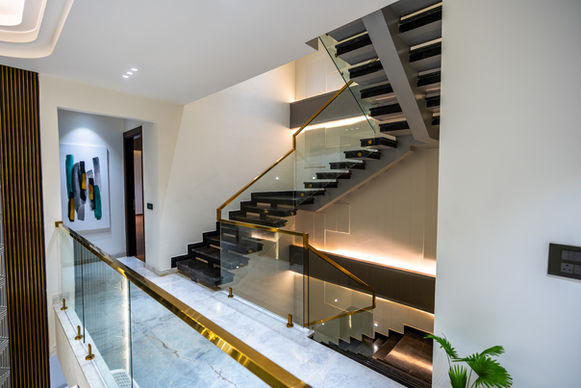 Modern staircase with glass railing and black steps, residential interior design.