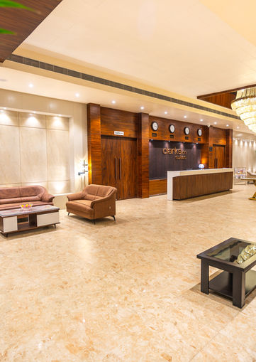 Architectural photograph of a hotel lobby with seating, reception desk and chandelier; in a welcoming space.