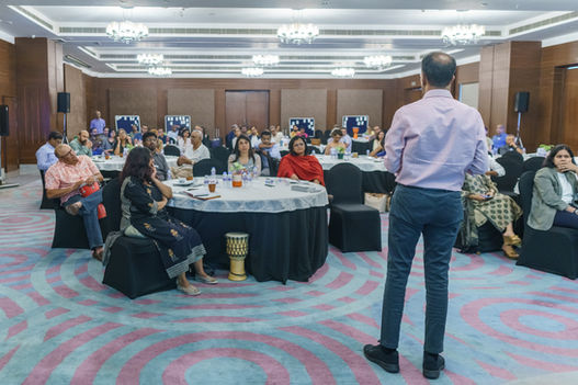 Speaker addresses audience at a conference in a large room setting.