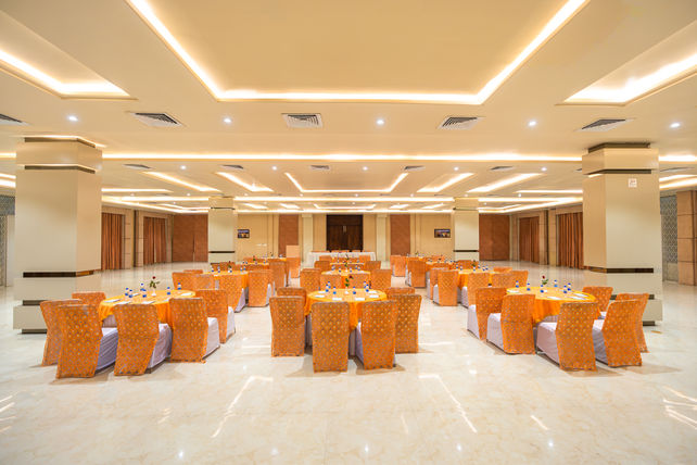Architectural photograph of an elegant banquet hall with orange tables and chairs.