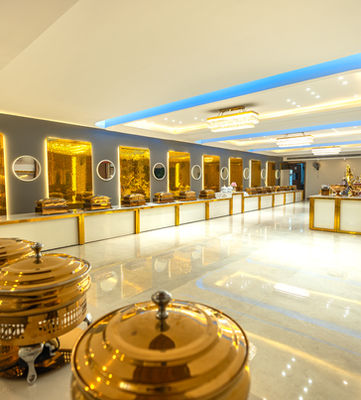 Architectural photograph of a buffet setup with golden serving dishes in an events hall of a hotel.