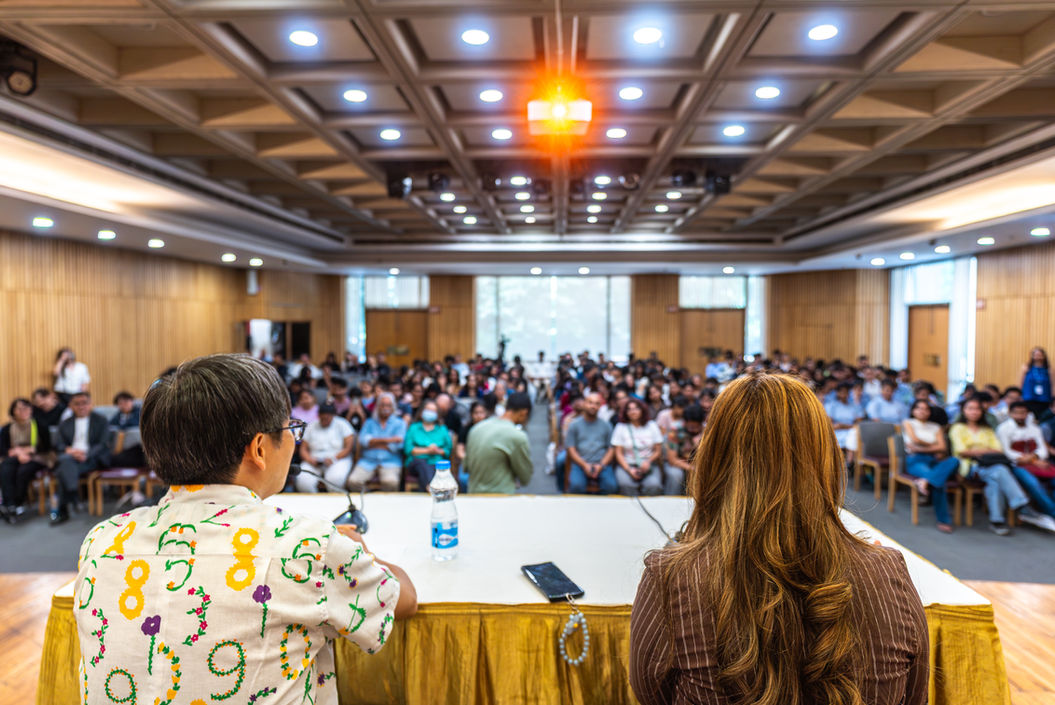 Speakers at table face large audience in conference hall EVENTS