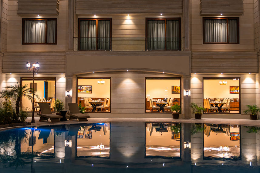 Architectural photograph of a hotel exterior at night with pool reflection and lit windows.