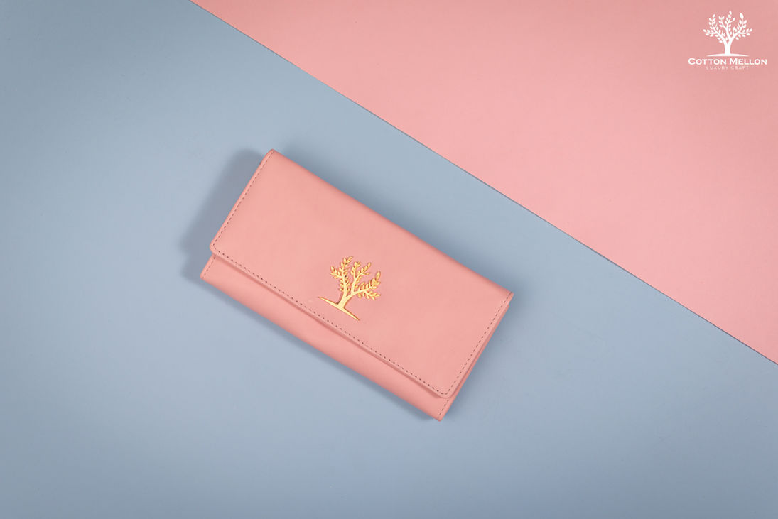 Pink wallet with a gold tree logo on a blue and pink background.