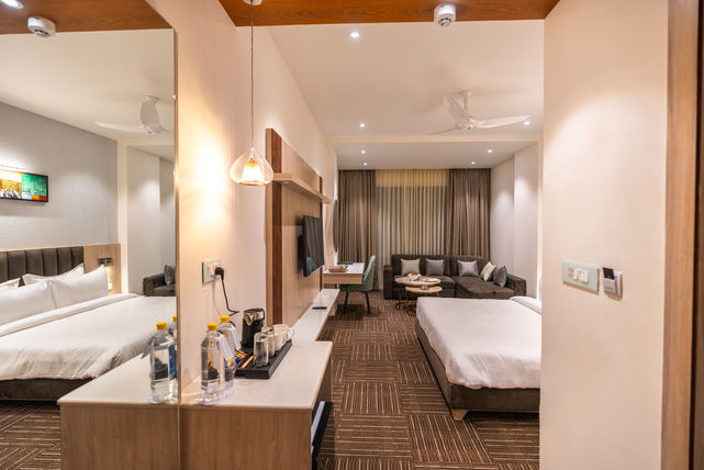 Architectural photograph of hotel room with bed, sofa, TV, desk for comfortable working along  with a cozy lighting setup.