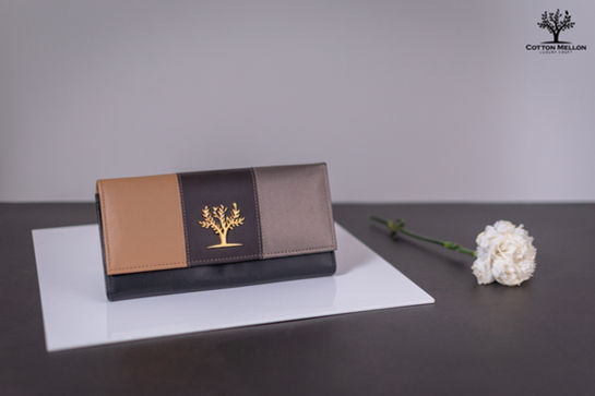 Elegant leather clutch with gold tree design, sitting on white surface