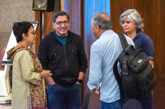 A group of people are talking at an event, smiling, wearing casual clothes.