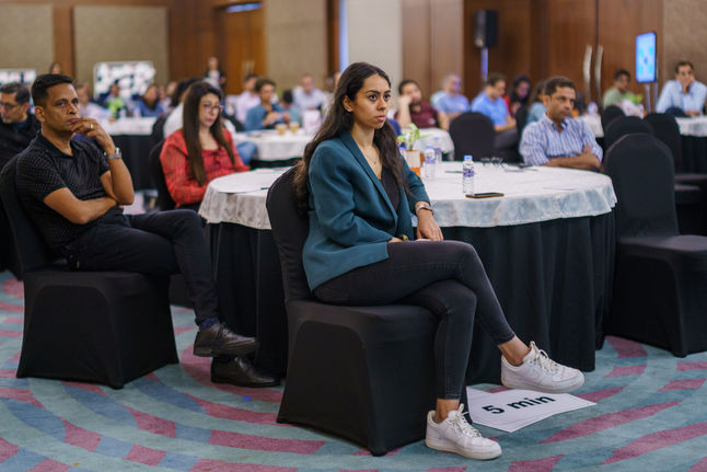 Woman sitting attentively at a conference, listening to a presentation intently with others.