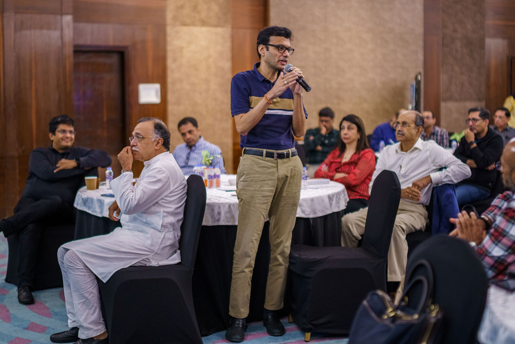 Man with glasses speaking into microphone during a conference presentation to audience