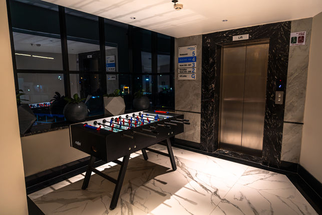 Architectural photograph of a foosball table and elevator in a modern hotel lobby area.