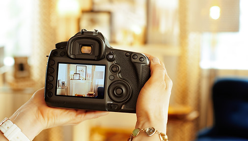 Closeup on modern DSLR camera in hand of modern female interior photographer at home..jpg