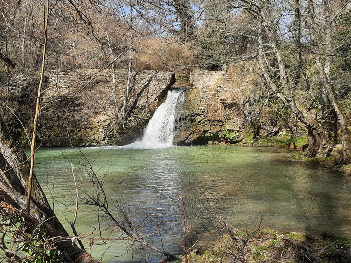 piccola cascata in un bosco che fuoriesce da un antico acquedotto e cade in un piccolo lago sottostante