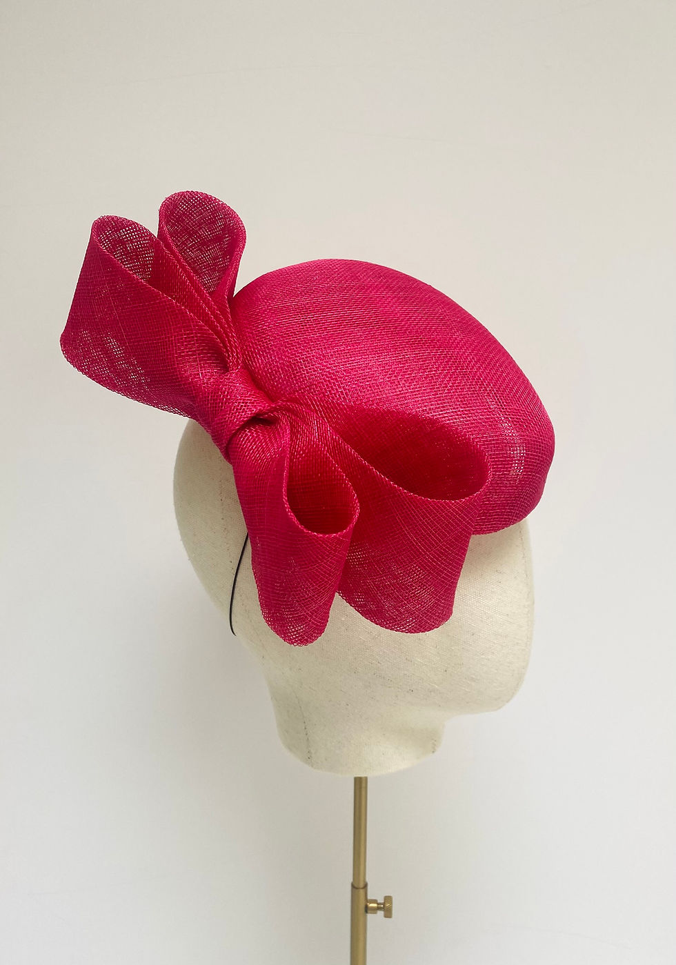 Thumbnail: A bright pink wedding hat with a bow is displayed on a mannequin head