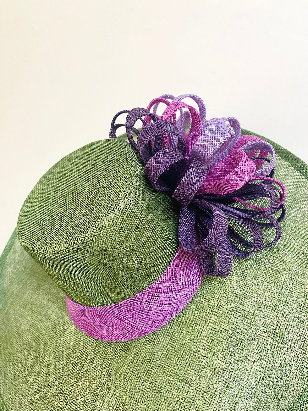 Thumbnail: A large brimmed green hat with purple decoration is displayed on a mannequin head