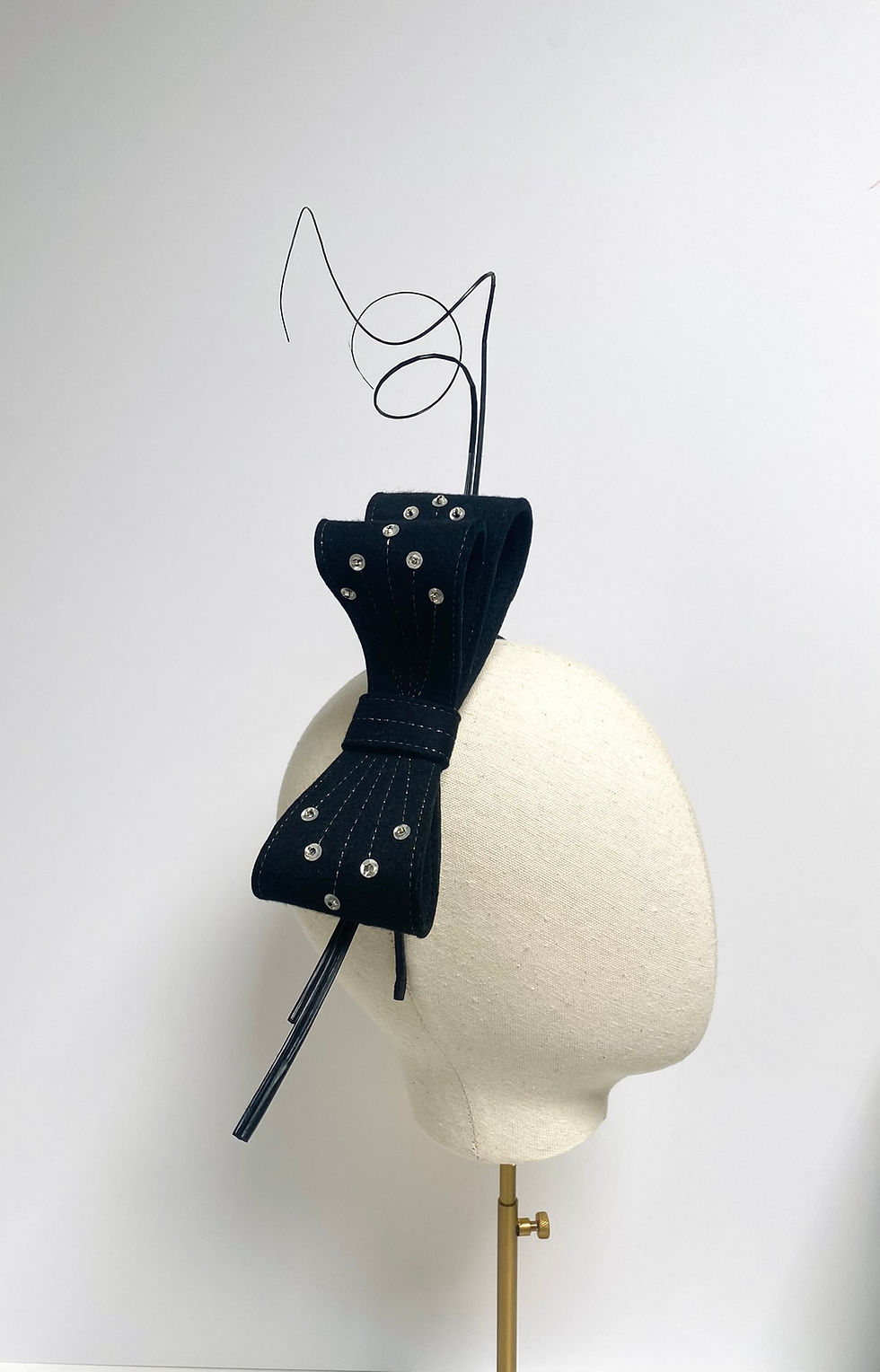 Thumbnail: A large black felt bow headband decorated with ostrich quill feathers and silver sequins is displayed on a mannequin head