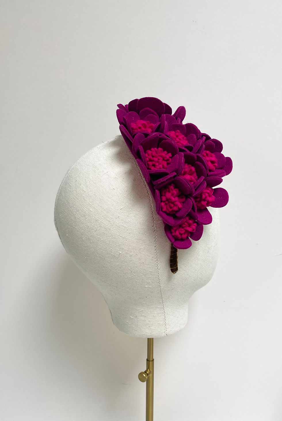 Thumbnail: A hot pink felt floral headpiece is displayed on a mannequin head