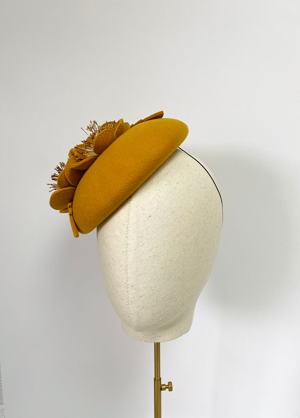 Thumbnail: A yellow felt wedding hat with matching flowers is displayed on a mannequin head
