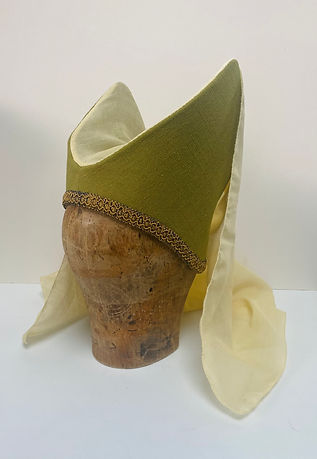 A side view of a green fabric medieval headdress with cream veiling is displayed on a wooden block