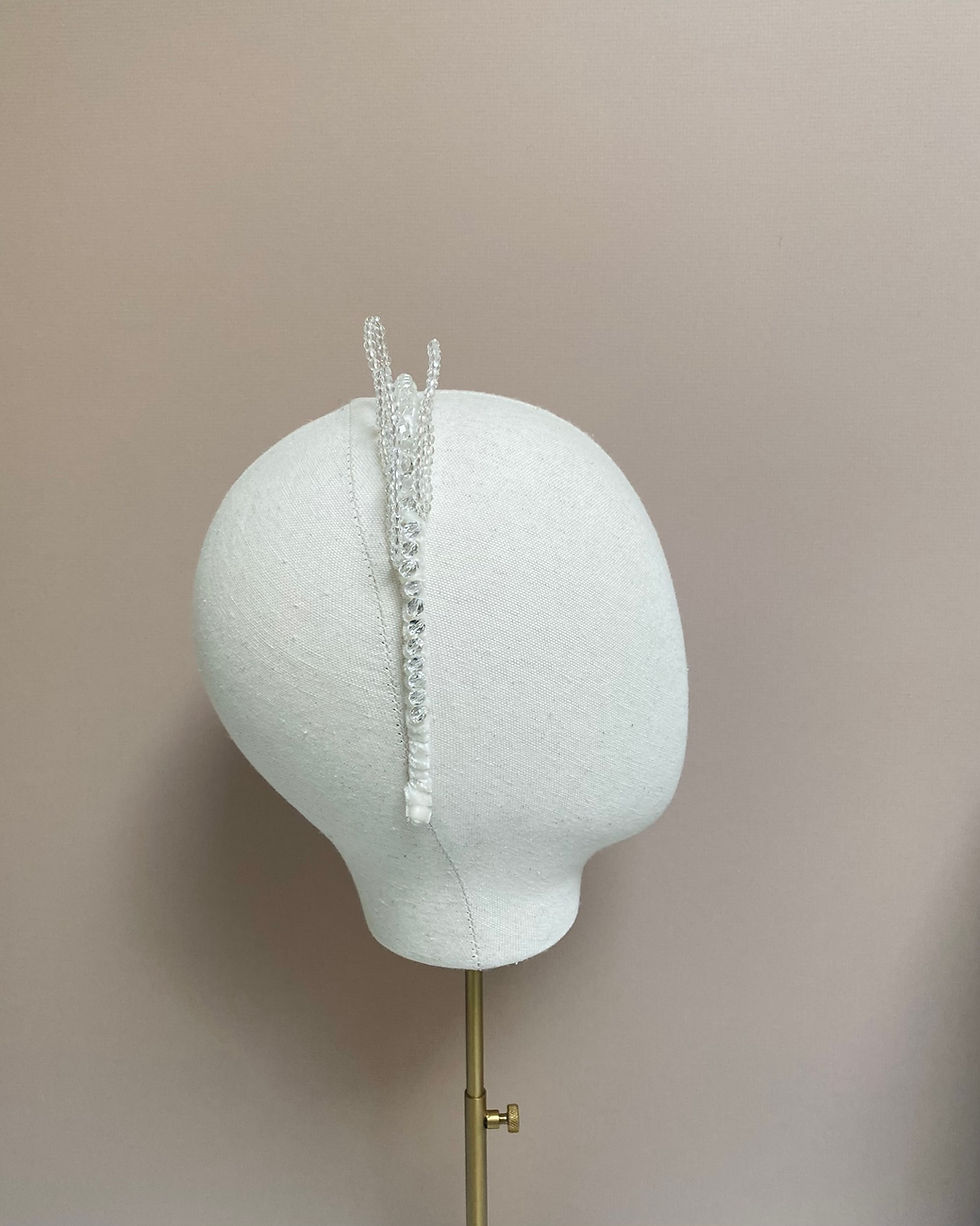 Thumbnail: A crystal beaded ivory ribbon headband with crystal leaves is displayed on a mannequin head.