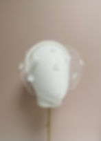 Front view of a bridal birdcage veil with flowers displayed on a mannequin head