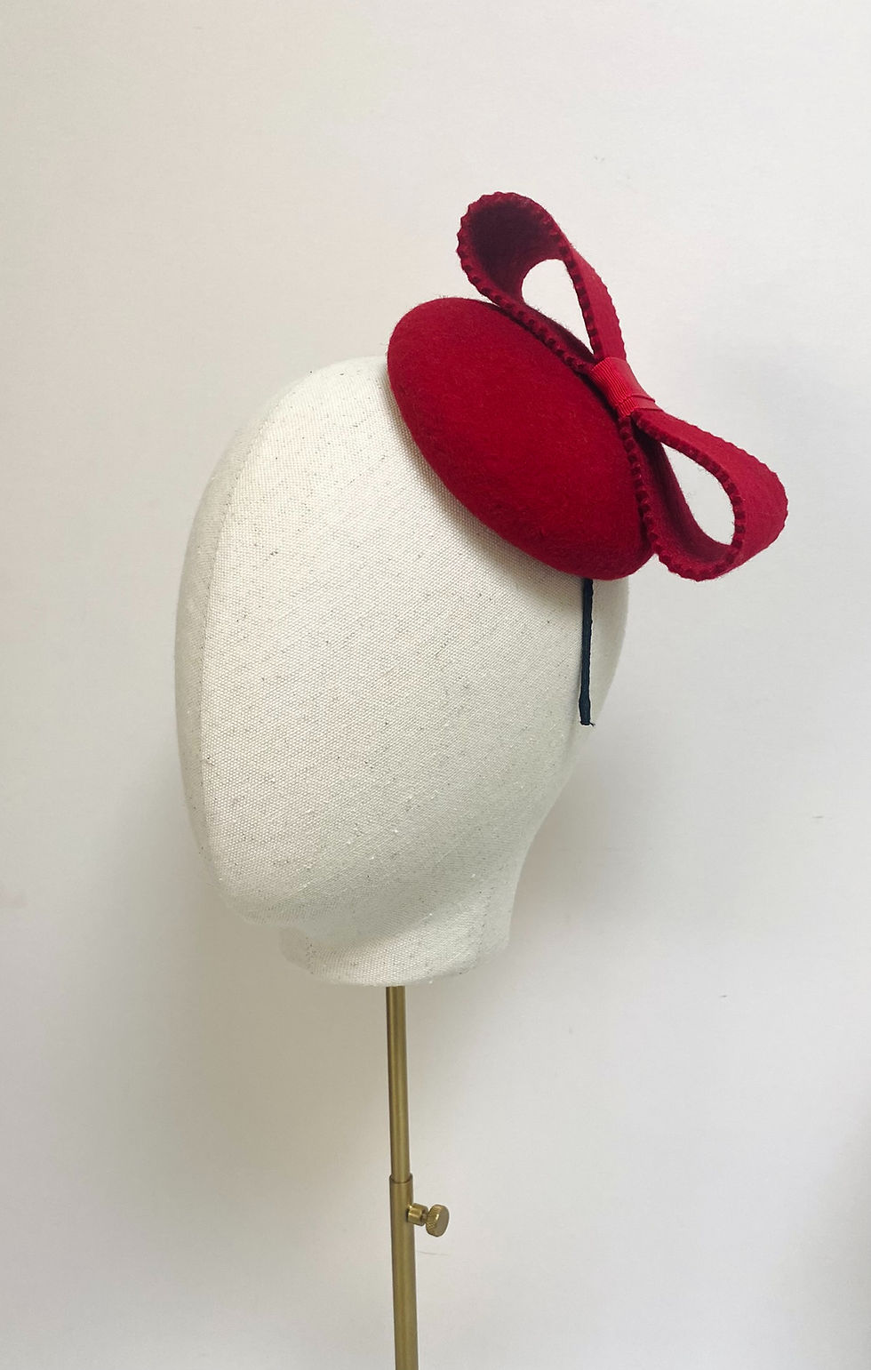 Thumbnail: A small red felt hat with matching bow is displayed on a mannequin head