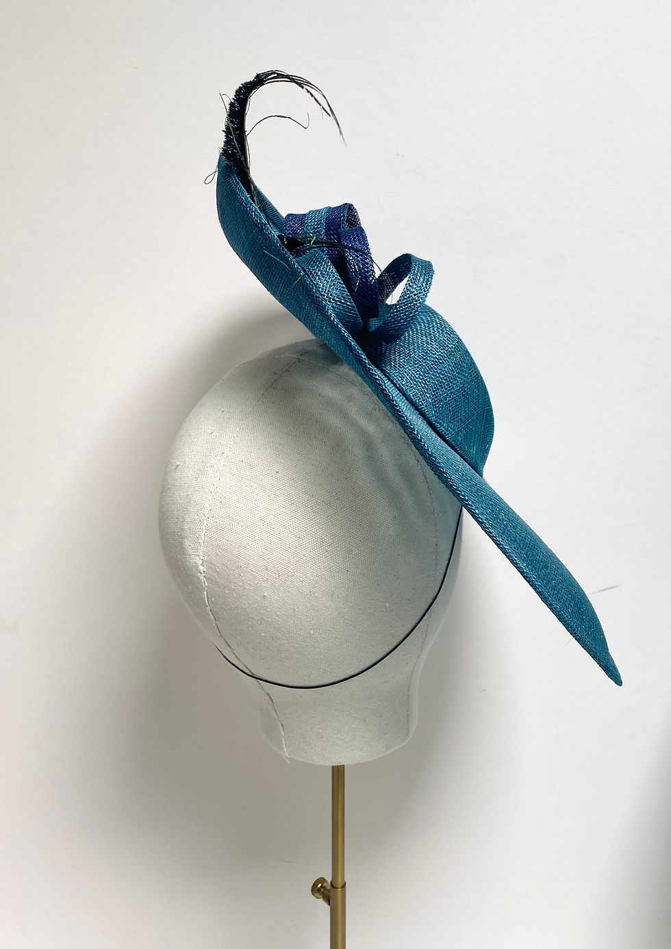 Thumbnail: A large brimmed blue sinamay wedding hat with striped bows is displayed on a mannequin head