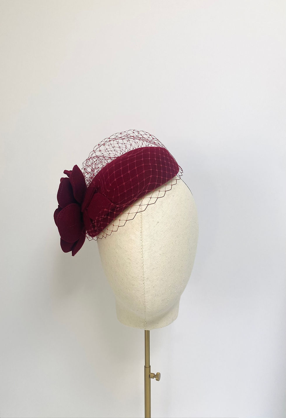 Thumbnail: A dark red felt flower wedding hat with a veil is displayed on a mannequin head