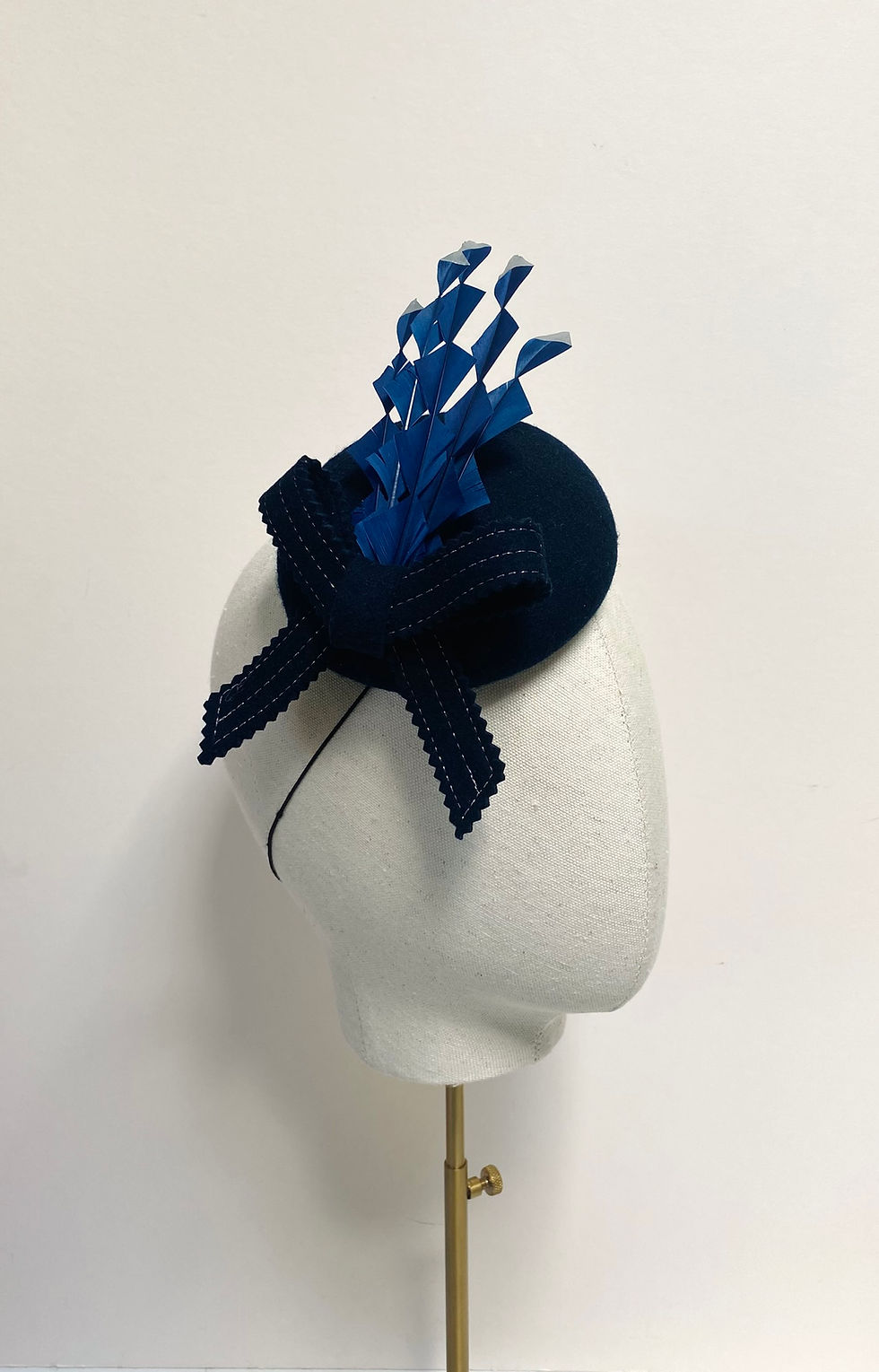 Thumbnail: A navy felt fascinator with silver tipped feathers is displayed on a mannequin head