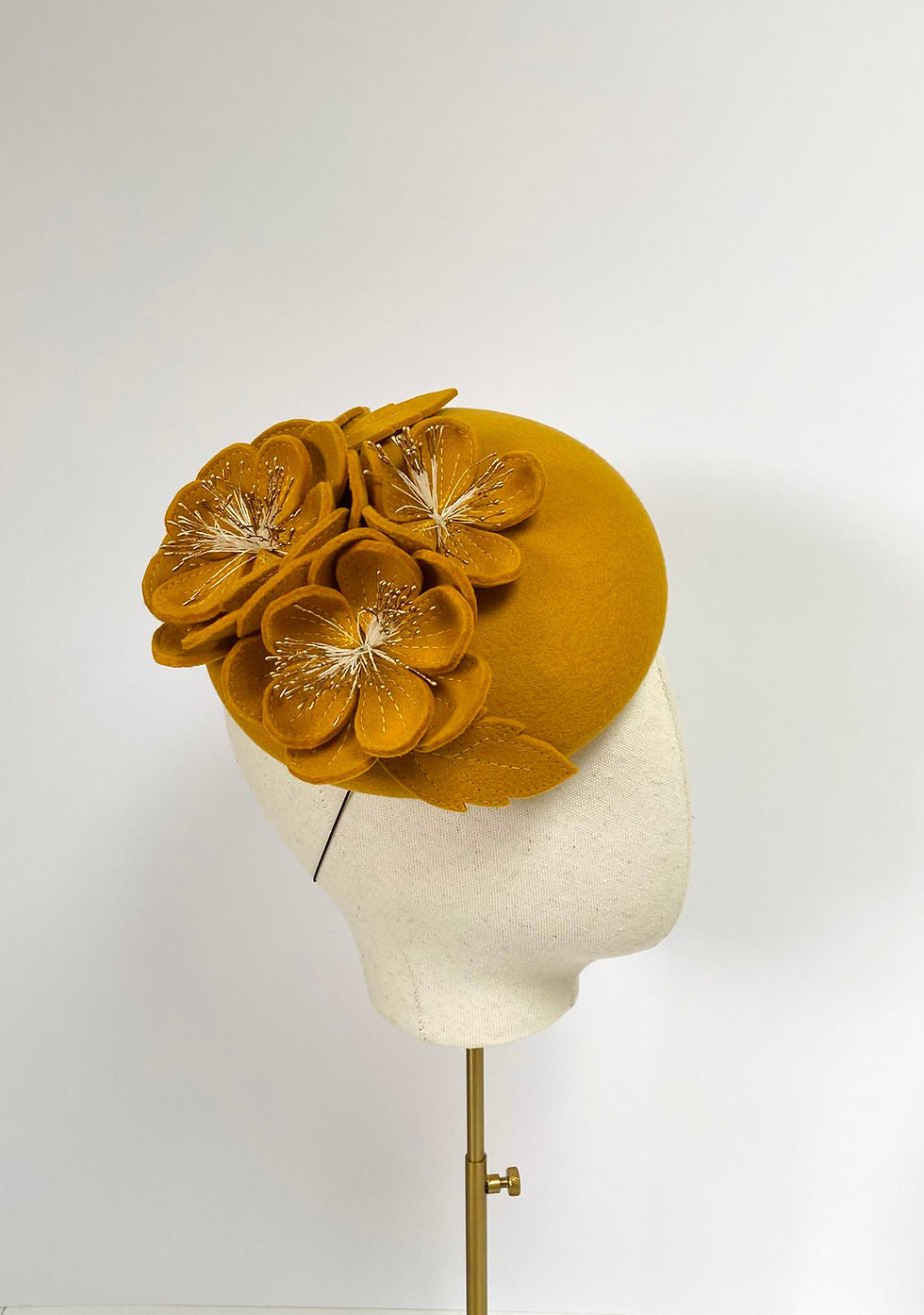 Thumbnail: A yellow felt wedding hat with matching flowers is displayed on a mannequin head