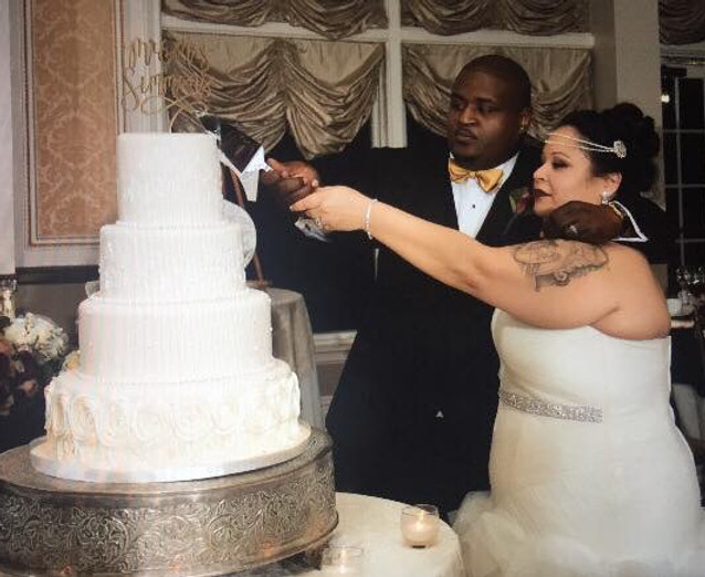 Side view of a bride and groom cutting a cake