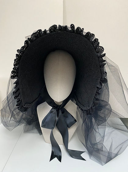 Front view of a black straw bonnet with veiling displayed on a mannequin head