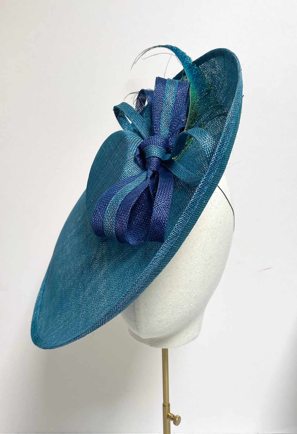 Thumbnail: A large brimmed blue sinamay wedding hat with striped bows is displayed on a mannequin head